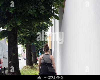 Cremona, Italien - 27. Mai 2024 Frau spaziert durch die Stadt, hört Musik, vorbei an Bäumen und modernen Gebäuden und genießt die friedliche urbane Oase. Stockfoto