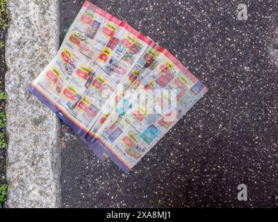 Cremona, Italien - 27. Mai 2024 ein farbenfroher Flyer, der die Auswirkungen von Werbung auf die Umwelt veranschaulicht, ist verworfen worden Stockfoto