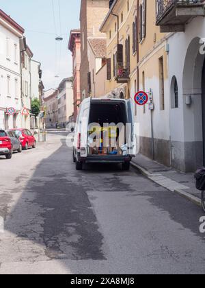 Cremona, Italien - 27. Mai 2024 Weißer Lieferwagen wird entladen, mit Pappkartons und einem Handwagen, der hinten sichtbar ist. Der Van steht auf einem Narr Stockfoto