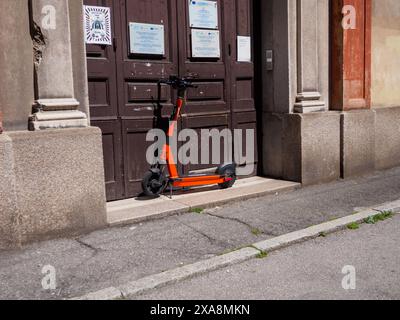 Cremona, Italien - 27. Mai 2024 Orange Elektroroller parkte vor einem Gebäudeeingang und repräsentiert den städtischen Pendelverkehr und die wachsende Popularität von Stockfoto