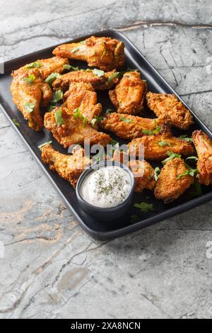 Knusprig gebackene Curry-panierte Hähnchenflügel in Nahaufnahme auf einem Teller auf dem Tisch. Vertikal Stockfoto