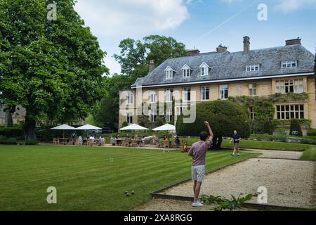 Teenager spielen Boules in den Gärten des Slaughters Manor House in Lower Slaughter im Frühjahr Stockfoto