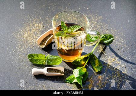 Pfefferminze, hybride Pfefferminze (Mentha x piperita, Mentha piperita, M. aquatica x M. spicata), frischer Spross mit getrockneten und zerstoßenen Blättern für Tee, Glas Stockfoto