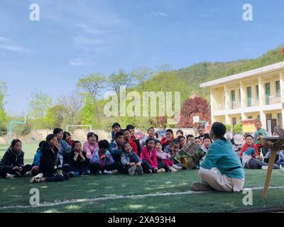 XI'an, chinesische Provinz Shaanxi. April 2024. Dieses Foto mit einem Mobiltelefon zeigt Jiao Meining, der am 18. April 2024 an der Renzong Central Primary School im Bezirk Lintong in Xi'an, Provinz Shaanxi im Nordwesten Chinas, einen Bilderbuchkurs hält. ZU „Profil: Buchhandlung-Besitzer bringt Geschichten, Wechsel zu Kindern im ländlichen China“ Credit: Sun Zhenghao/Xinhua/Alamy Live News Stockfoto