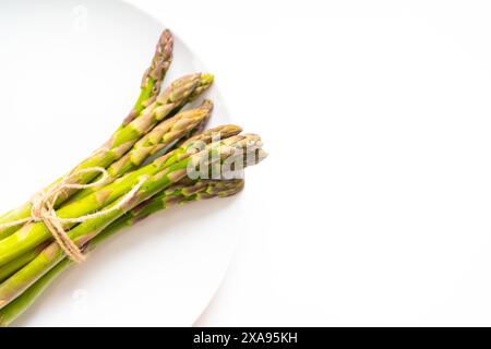 Ein Haufen roher Gartenspargel mit isoliertem Schatten. Frisches grünes Frühlingsgemüse auf weißem Hintergrund. Essbare Spargelsprossen, Draufsicht. Hohe Qual Stockfoto