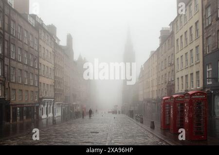 Edinburgh, Schottland, Großbritannien; 13.06.2020: Blick auf die Royal Mile in der Altstadt, mit Nebel, Menschen zu Fuß und drei britischen roten Telefonzellen im Vordergrund Stockfoto