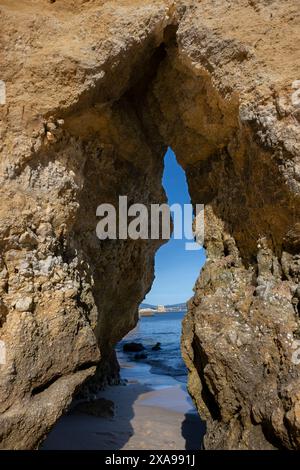 Blick auf den Atlantischen Ozean, durch einen Steinbogen am Strand, Praia da Boneca, Ponta da Piedadeca, Lagos, Faro, Portugal Stockfoto