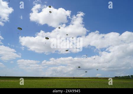 Mitglieder des britischen, belgischen, kanadischen und US-Militärs nehmen an einer Fallschirmspringshow Teil, die von der Royal Air Force und der britischen Armee in der "Drop Zone K" in der Nähe von Sannerville (Frankreich) organisiert wird, um die Rolle der Luftwaffe während der Landungen in der Normandie zu gedenken; vor dem 80. Jahrestag des D-Day. Bilddatum: Mittwoch, 5. Juni 2024. Stockfoto