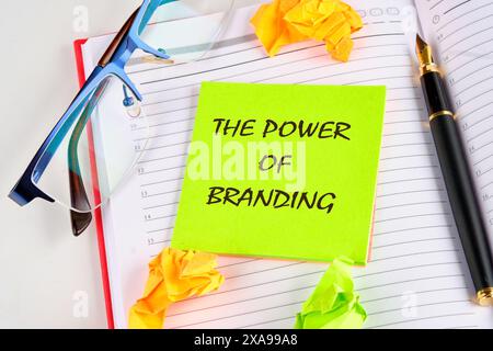Die Macht des Brandings auf einem hellgrünen Aufkleber auf einem Notizblock in der Nähe von Brillen, einem Stift und zerknittertem Papier Stockfoto