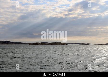 Sonnenlicht durch Wolken über den äußeren Inseln im Fjällbacka-Archipel an der Westküste Schwedens. Stockfoto