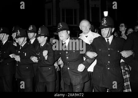 Karnevalsaufstand in Notting Hill, Bankfeiertag im August. 1979. Vater Michael Hollings örtlicher römisch-katholischer Pfarrer von St. Mary of the Angels, Notting Hill. Er steht hinter der Polizeikabine, die an der All Saints Road errichtet wurde. Notting Hill, London, England, 1970er Jahre Großbritannien HOMER SYKES Stockfoto