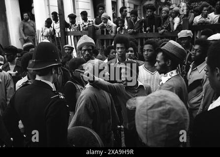 Karnevalsaufstand in Notting Hill August Bankfeiertag Montag 1976. Die Polizei versucht, eine friedliche Gruppe schwarzer britischer Rastafarier zu bekämpfen, die friedlich trommeln und singen. Ein wütender junger Rastafarier lässt die Polizei wissen, was er denkt, und ein Ältester will ihn beruhigen. Notting Hill, London, England, 30. August 1976. HOMER SYKES AUS DEN 1970ER JAHREN Stockfoto