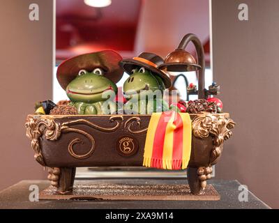 HANDWERKLICHE SCHOKOLADENFIGUREN FRÖSCHE KITSCHIG in einem Bad zum Verkauf aus Schokolade im renommierten Geschäft Le Comptoir du Chocolat Quimper Brittany Frankreich Stockfoto