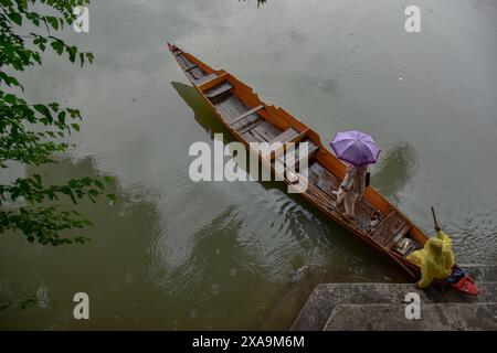 Srinagar, Indien. Juni 2024. Eine Frau hält einen Schirm, während sie bei Regenfällen in Srinagar, der Sommerhauptstadt von Jammu und Kaschmir, an Bord eines Bootes geht. (Foto: Saqib Majeed/SOPA Images/SIPA USA) Credit: SIPA USA/Alamy Live News Stockfoto