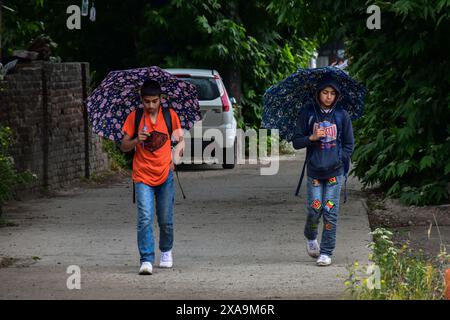 Srinagar, Indien. Juni 2024. Pendler halten Schirme, während sie während des Regenfalls in Srinagar, der Sommerhauptstadt von Jammu und Kaschmir, auf der Straße spazieren gehen. (Foto: Saqib Majeed/SOPA Images/SIPA USA) Credit: SIPA USA/Alamy Live News Stockfoto