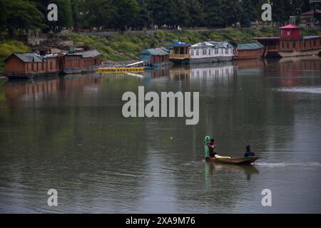 Srinagar, Indien. Juni 2024. Ein Fischer (L) bereitet sich darauf vor, bei Regenfällen in Srinagar, der Sommerhauptstadt von Jammu und Kaschmir, ein Netz im Fluss Jehlum zu werfen. (Foto: Saqib Majeed/SOPA Images/SIPA USA) Credit: SIPA USA/Alamy Live News Stockfoto