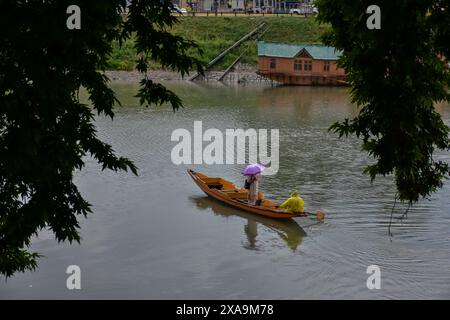 Srinagar, Indien. Juni 2024. Ein Bootsmann (R) überquert den Fluss Jehlum bei Regenfällen in Srinagar, der Sommerhauptstadt von Jammu und Kaschmir. (Foto: Saqib Majeed/SOPA Images/SIPA USA) Credit: SIPA USA/Alamy Live News Stockfoto