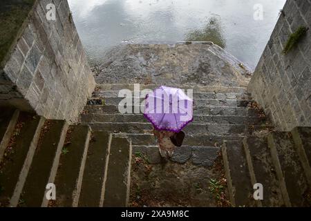 Srinagar, Indien. Juni 2024. Eine Frau hält einen Regenschirm, während sie bei Regenfällen in Srinagar, der Sommerhauptstadt von Jammu und Kaschmir, die Treppe hinuntergeht. (Foto: Saqib Majeed/SOPA Images/SIPA USA) Credit: SIPA USA/Alamy Live News Stockfoto