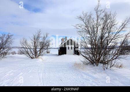 Schneebedeckte Kabine auf dem Feld, umgeben von Bäumen Stockfoto