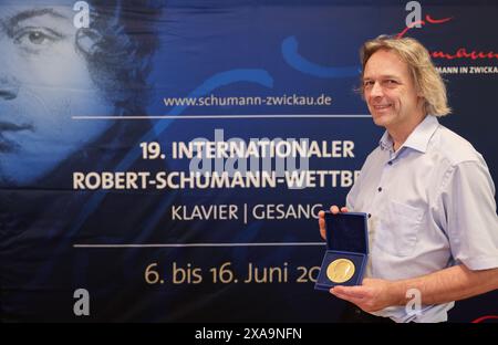 05. Juni 2024, Sachsen, Zwickau: Thomas Synofzik, Direktor des Robert-Schumann-Hauses und Vorsitzender der Jury des Internationalen Robert-Schumann-Wettbewerbs für Klavier und Gesang, steht vor einem Logo der Veranstaltung. In den nächsten zehn Tagen werden 66 junge Pianisten und 79 Sängerinnen und Sänger erwartet, darunter auch einige aus Asien und Amerika. Die Stadt Zwickau, in der der Komponist Robert Schumann geboren wurde, veranstaltet alle vier Jahre den nach ihm benannten Musikwettbewerb. Dieses Jahr findet sie vom 6. Bis 16. Juni zum 19. Mal statt. Die Preise für die besten Virtuosen werden mit bis zu 10.000 Preisen bestückt Stockfoto