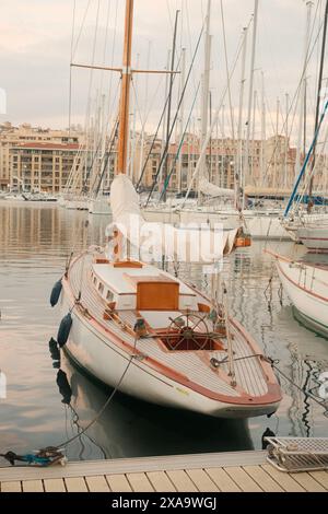 Ein weißes Segelboot legte in einem geschäftigen Yachthafen an, neben zahlreichen anderen Booten Stockfoto