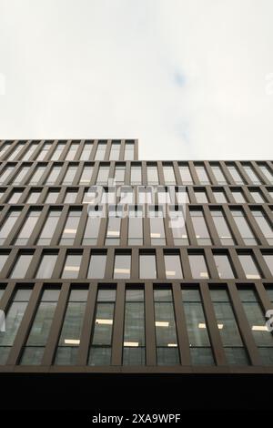 Sonnenlicht beleuchtet ein hohes Glasgebäude, von unten betrachtet Stockfoto