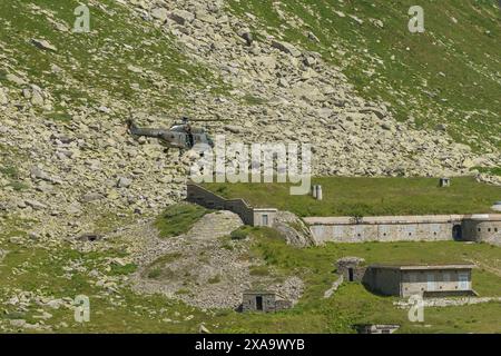 Zwei Hubschrauber parkten auf Gras in der Nähe von Klippen bei kleinen Gebäuden Stockfoto