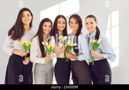 Porträt schöner glücklicher Frauen mit Blumen in Händen, die den internationalen Frauentag feiern. Stockfoto