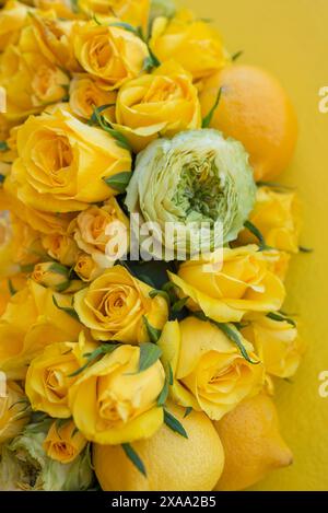 Ein Foto von Blumen, Zitronen und Rosen auf gelbem Hintergrund Stockfoto