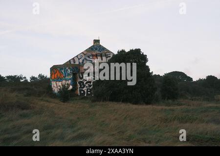 Ein altes Gebäude auf einem Hügel mit Graffiti und einem wilden Feld in Saint Nazaire, Frankreich Stockfoto