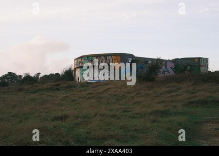 Ein altes Gebäude auf einem Hügel mit Graffiti und einem wilden Feld in Saint Nazaire, Frankreich Stockfoto