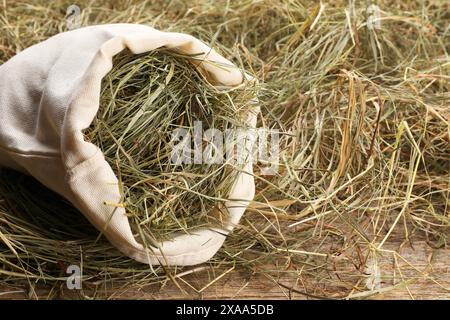 Getrocknetes Heu im Sack auf Holztisch, Nahaufnahme Stockfoto