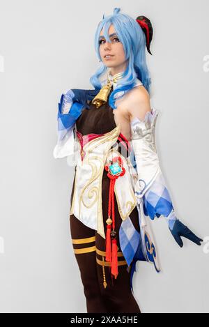 Eine weibliche Cosplayer mit blauen Haaren und einem ausgeklügelten Kleid, die sich vor neutralem Hintergrund posiert Stockfoto