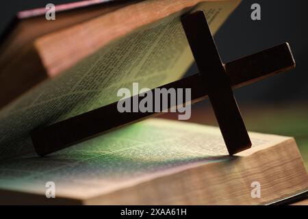 Kreuz und Bibel in farbigen Lichtern, Nahaufnahme. Religion des Christentums Stockfoto