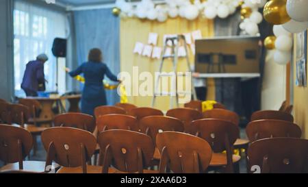 Die Lehrer bereiten den Saal für eine Schulveranstaltung vor. Konzentrieren Sie sich auf die Stühle. Stockfoto