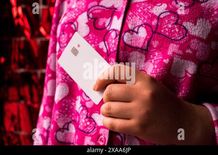 Eine Frau im Pyjama mit Herzen, die eine Kreditkarte hält Stockfoto