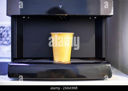 Verkaufsautomat mit einem Einweg-Becher aus recycelbarem Karton mit einem Heißgetränk. Umweltökologie Stockfoto