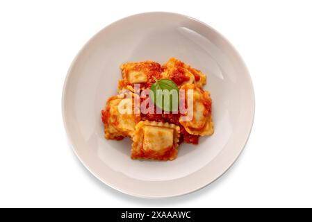 Ravioli mit Tomatensauce und Basilikumblatt in weißer Platte isoliert auf weiß mit Schnittpfad inbegriffen, Blick von oben Stockfoto