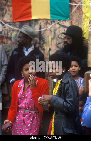 1970er Jahre Großbritannien zwei schwarze britische Teenager-Mädchen, die in modischen Kleidern der damaligen Zeit herumstehen. Notting Hill Karneval August Bankfeiertag Montag. London, England, 27. August 1979. HOMER SYKES Stockfoto