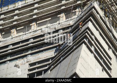 Zwei Bauarbeiter auf Gerüsten auf der Baustelle eines hohen Gebäudes Stockfoto