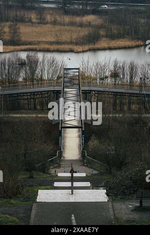 Eine verlassene Brücke am Flussufer, umgeben von blattlosen Bäumen Stockfoto