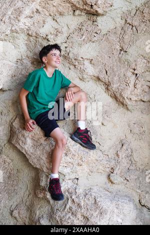 Junge, der auf einer Felswände sitzt Stockfoto
