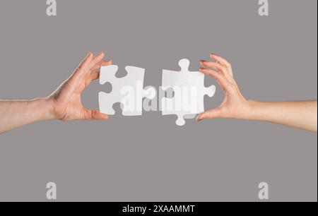 Puzzles. Mann und Frau halten ein Puzzle in der Hand. Geschäftslösungen, Erfolg und Strategiekonzept. Die Hände verbinden Puzzle. Hand des Mannes und Stockfoto