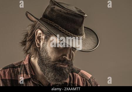 Cowboy-STYLE. Hübscher junger Mann, der seinen Cowboyhut anpasst. Cowboys im Hut. Schöner bärtiger Macho. Mann unrasierte Cowboys. Amerikanischer Cowboy. Leder Stockfoto