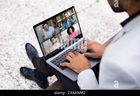 Geschäftsmann, der an einer Videokonferenz über Laptop im urbanen Außenbereich teilnimmt Stockfoto