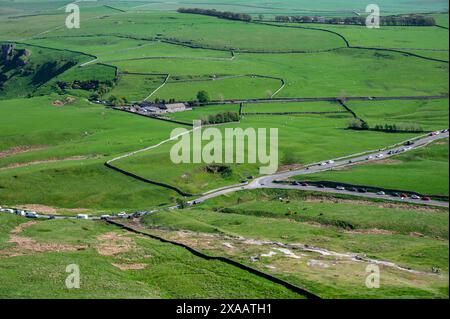 Blick aus der Vogelperspektive auf eine malerische Landschaft mit üppigen grünen Feldern, gewundenen Straßen und charmanten Landhäusern im Peak District Park, England. Stockfoto
