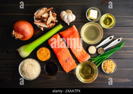Gebratener Lachs mit Pilz-Risotto Zutaten: Fischfilets, Arborio-Reis, Weißwein und andere rohe Zutaten auf einem Holztisch Stockfoto