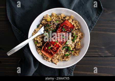 Gebratener Lachs mit Pilz-Risotto in einer Pasta-Schüssel: Mariniertes Lachsfischfilet auf einem Bett aus Pilzrisotto mit Zwiebeln und Sesamgarnitur Stockfoto