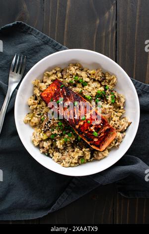Gebratener Lachs mit Pilz-Risotto in einer Pasta-Schüssel: Mariniertes Lachsfischfilet auf einem Bett aus Pilzrisotto mit Zwiebeln und Sesamgarnitur Stockfoto