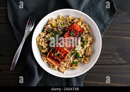 Gebratener Lachs mit Pilz-Risotto in einer Pasta-Schüssel: Mariniertes Lachsfischfilet auf einem Bett aus Pilzrisotto mit Zwiebeln und Sesamgarnitur Stockfoto